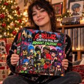 Woman holding a Gorillaz Cartoon Skull Riot 2026 Advent Calendar in a holiday setting.