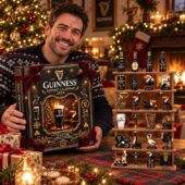 Man holding a 2026 Guinness advent calendar next to a display rack of 24 miniature collectibles from TheStripedcat
