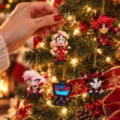 Hand holding Hazbin Hotel character Christmas ornaments on a decorated tree