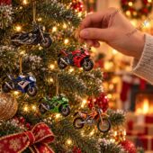 Hand holding a miniature motorcycle ornament hanging on a decorated Christmas tree